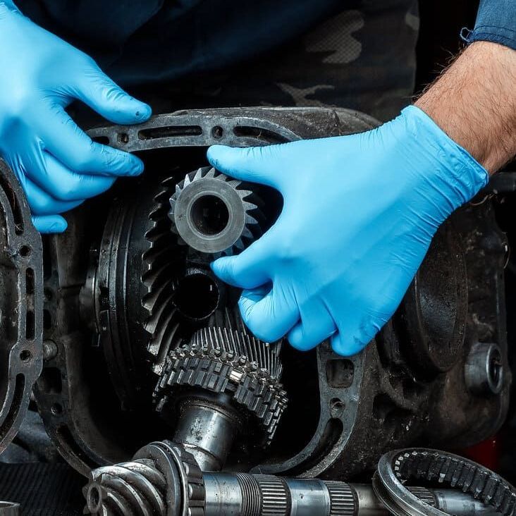 manos de mecanico con guantes azules sujeta piezas