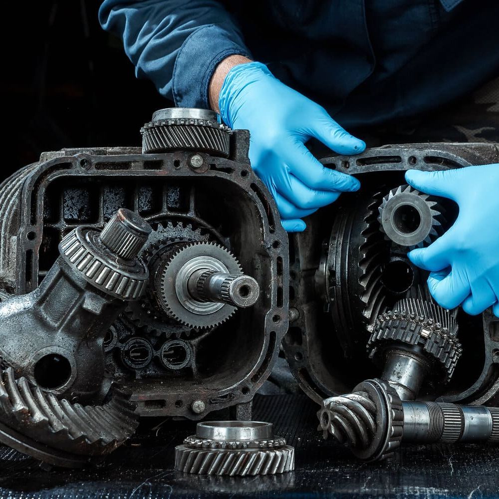 manos de mecanico con guantes azules sujeta piezas