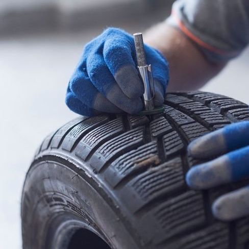 manos de mecanico con guantes sobre neumatico